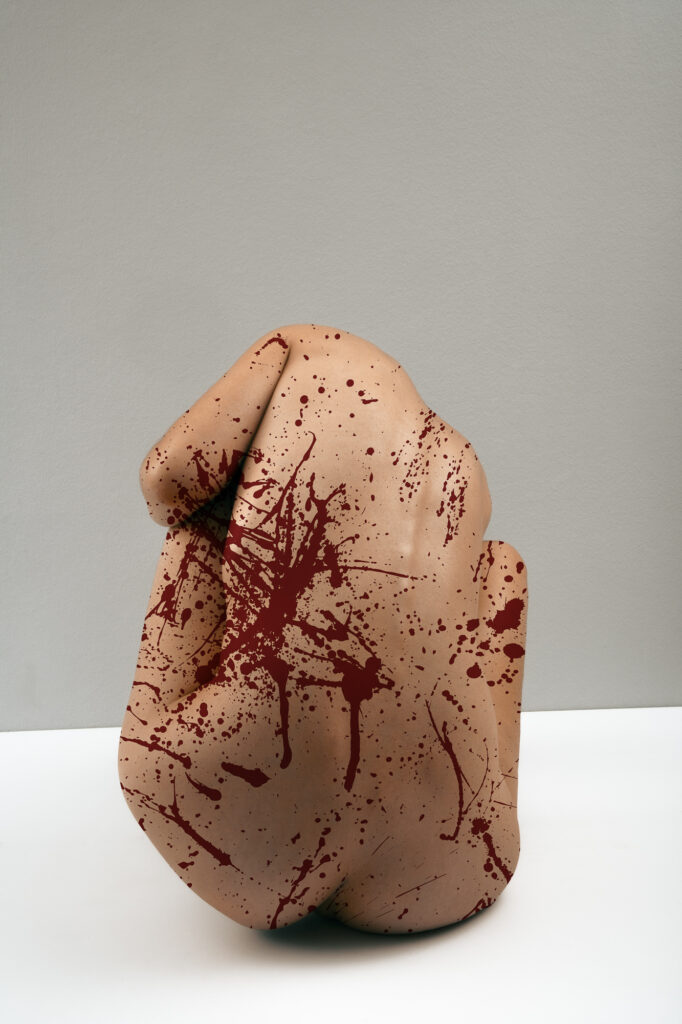 Edin Mustafic Fotografie, Serie Fleisch 2023: Skulpturaler, kopfloser menschlicher Torso mit drastischen roten Blutspritzern vor klinisch reinem Hintergrund.